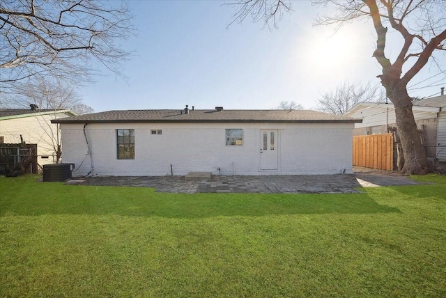 rear view of property with central AC unit and a lawn