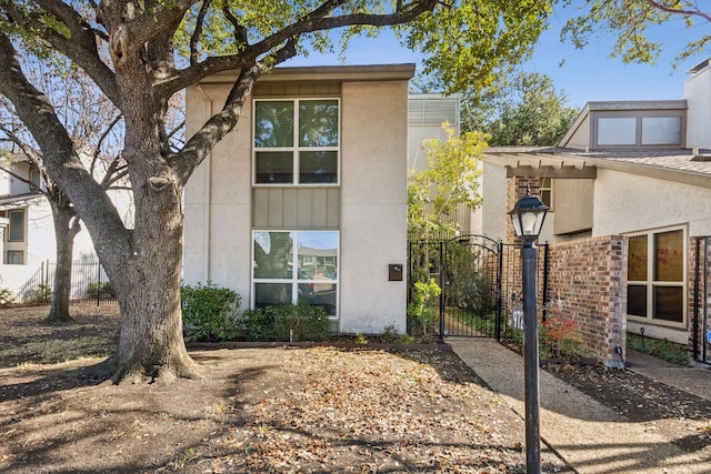 exterior space featuring brick siding, fence, a gate, and stucco siding