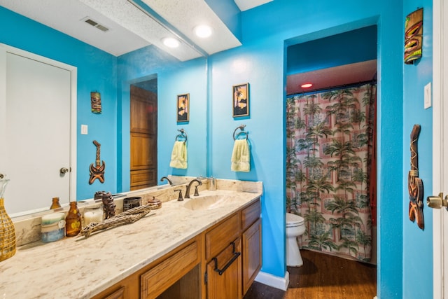 bathroom with a shower with curtain, vanity, a textured ceiling, hardwood / wood-style flooring, and toilet