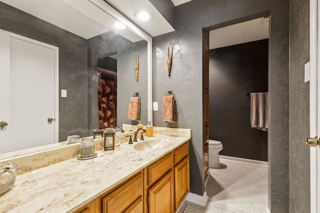 9728 Amberton Pkwy, Dallas, TX 75243 - bathroom with toilet, vanity, tile patterned flooring, a textured wall, and baseboards