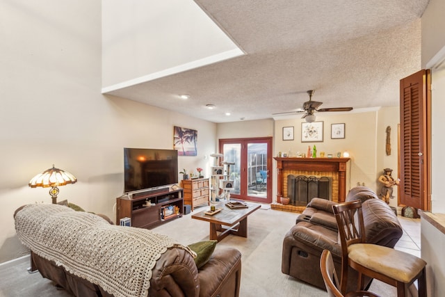 living area featuring a fireplace, a ceiling fan, and a textured ceiling