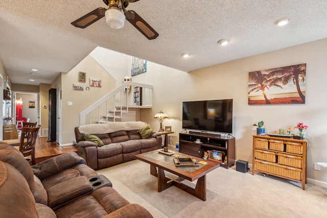 carpeted living room with ceiling fan and a textured ceiling