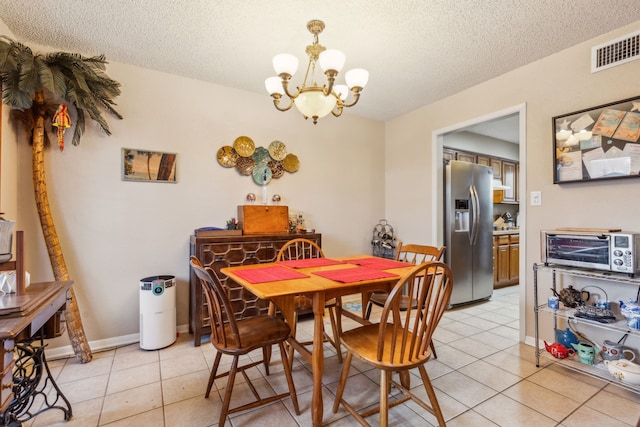 dining area with a chandelier, light tile patterned floors, and a textured ceiling