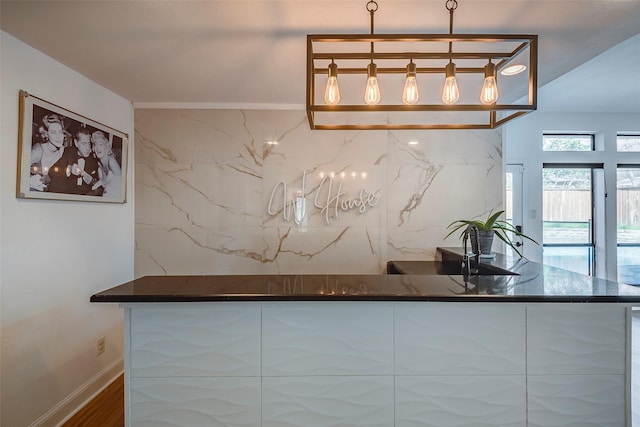 interior space with dark stone countertops, hardwood / wood-style floors, and decorative light fixtures