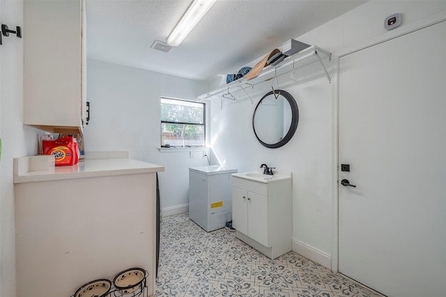 laundry area with sink, cabinets, and a textured ceiling