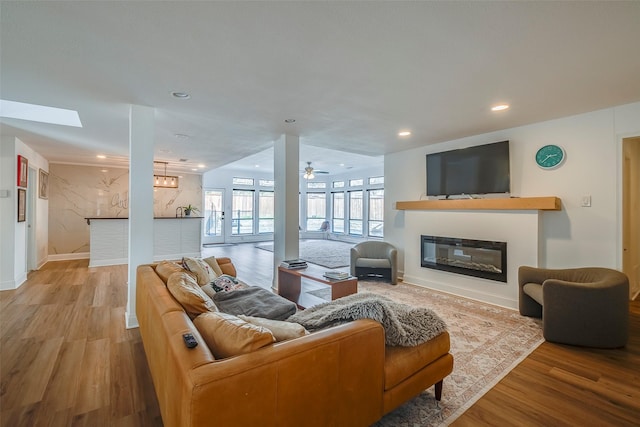 living room featuring light wood-type flooring, a skylight, and ceiling fan