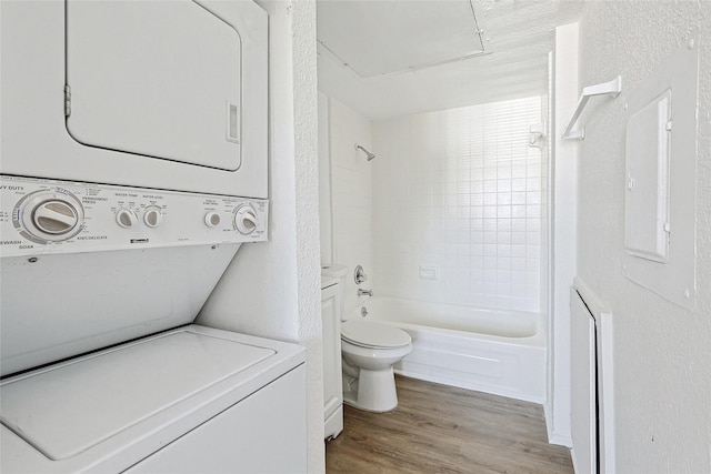 bathroom featuring hardwood / wood-style floors, electric panel, stacked washer and clothes dryer, toilet, and shower / bathtub combination