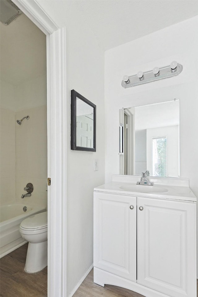 full bathroom with hardwood / wood-style floors, tiled shower / bath combo, toilet, and vanity