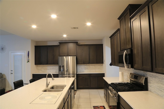 kitchen with light tile patterned flooring, appliances with stainless steel finishes, tasteful backsplash, and sink