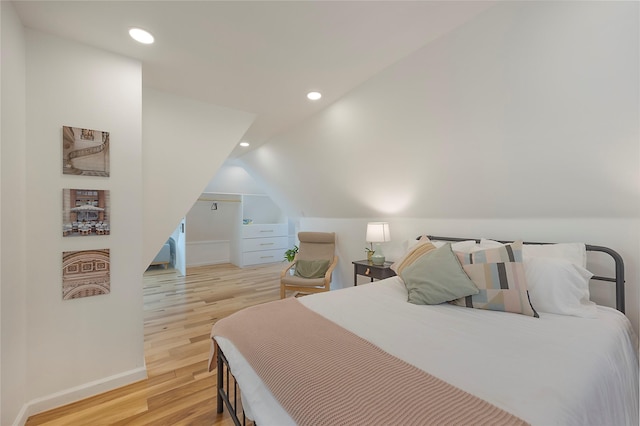 bedroom with light hardwood / wood-style floors and lofted ceiling