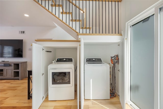 clothes washing area with washing machine and dryer and hardwood / wood-style flooring