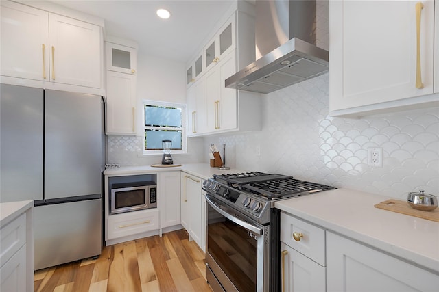 kitchen with wall chimney exhaust hood, white cabinetry, backsplash, and appliances with stainless steel finishes