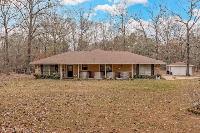 view of front facade with an outbuilding, a front lawn, covered porch, and a garage