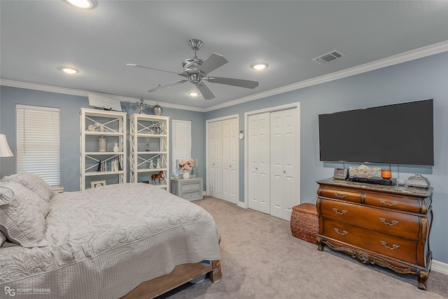 carpeted bedroom with ceiling fan, ornamental molding, and multiple closets