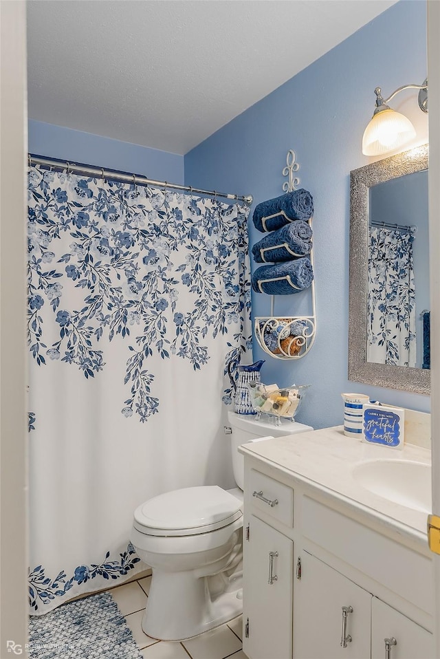 bathroom with toilet, vanity, and tile patterned flooring