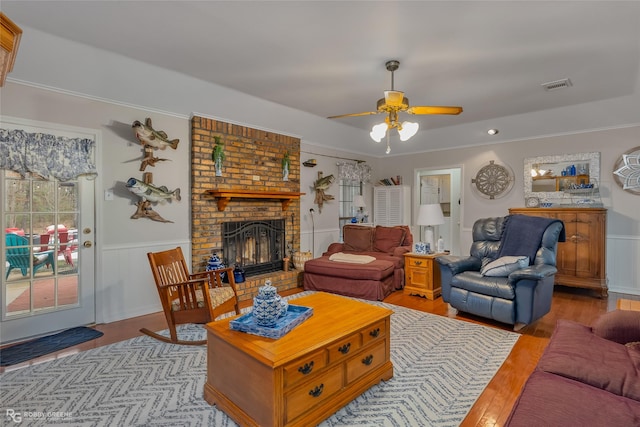 living room with ceiling fan, a brick fireplace, and light hardwood / wood-style floors