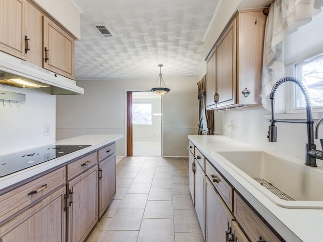 kitchen featuring black electric stovetop, pendant lighting, light tile patterned floors, and sink