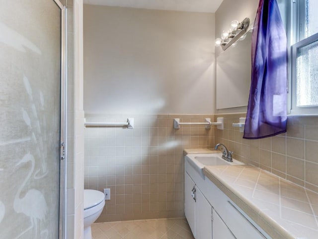 bathroom with vanity, tile patterned floors, toilet, tile walls, and a shower with shower door