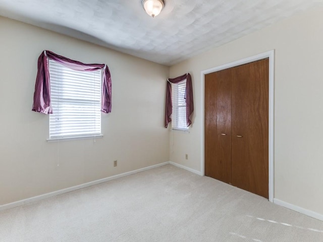 unfurnished bedroom featuring a closet and light colored carpet