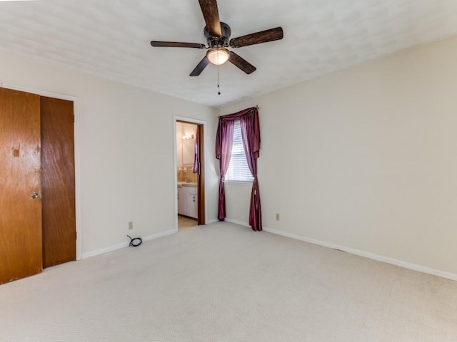 unfurnished bedroom with a closet, light colored carpet, ensuite bath, and ceiling fan