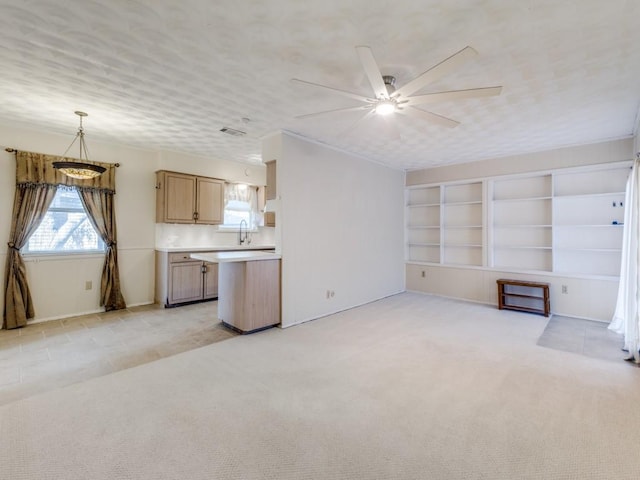 unfurnished living room with ceiling fan, light colored carpet, and sink