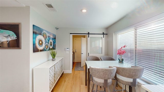 dining area featuring a barn door and light hardwood / wood-style floors