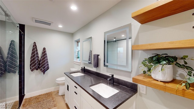 bathroom with a shower with door, vanity, and toilet