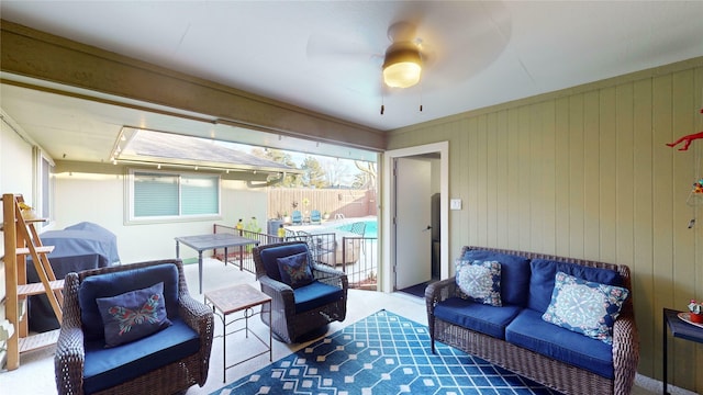 living room with ceiling fan, carpet floors, and wood walls