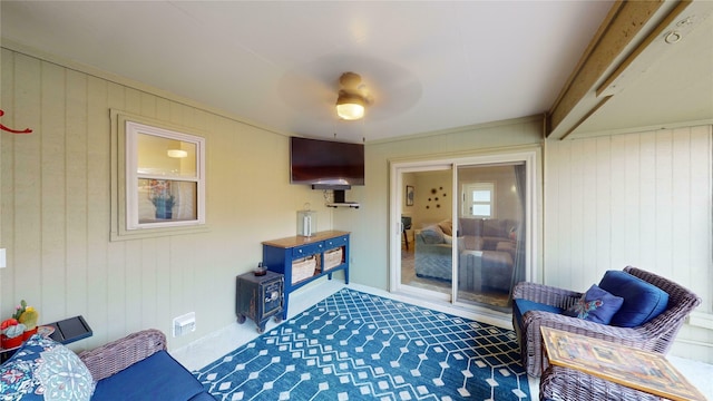 interior space featuring ceiling fan, wood walls, and ornamental molding