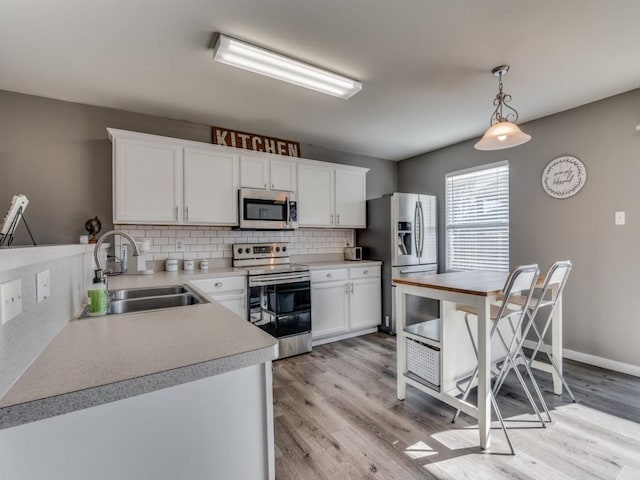 kitchen with appliances with stainless steel finishes, backsplash, sink, pendant lighting, and white cabinets