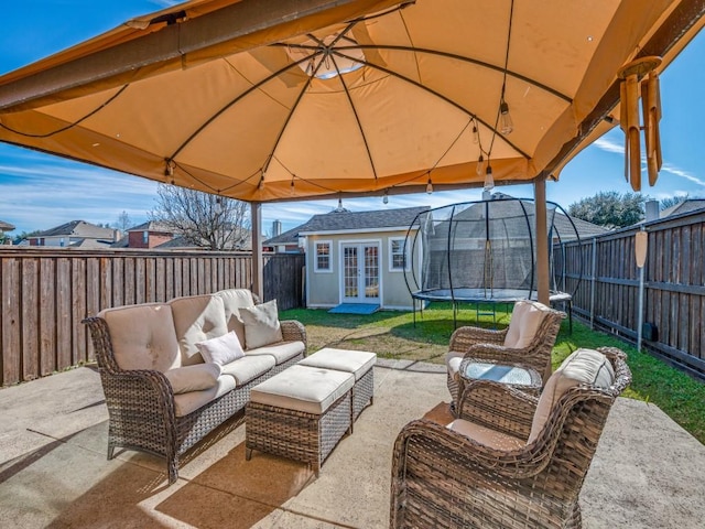 view of patio with french doors, an outdoor hangout area, an outdoor structure, a gazebo, and a trampoline