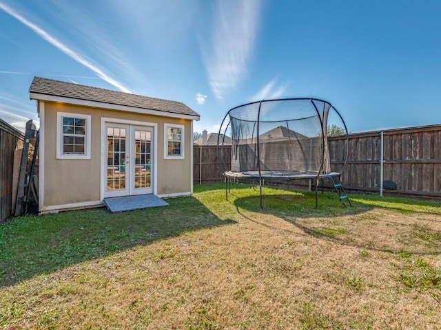 view of yard featuring a trampoline, an outdoor structure, and french doors