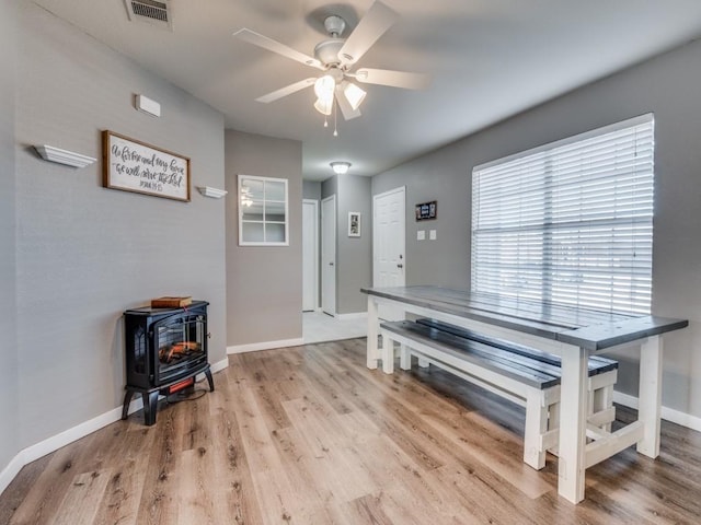 miscellaneous room with a wood stove, ceiling fan, and hardwood / wood-style flooring