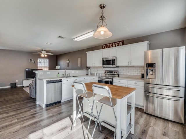 kitchen with appliances with stainless steel finishes, ceiling fan, pendant lighting, a center island, and white cabinetry