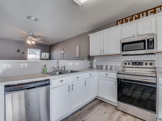 kitchen featuring kitchen peninsula, stainless steel appliances, ceiling fan, sink, and white cabinetry