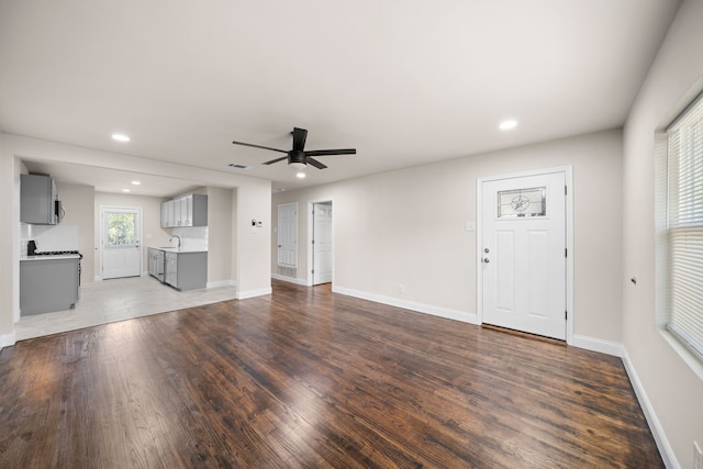 unfurnished living room with ceiling fan, hardwood / wood-style floors, and sink