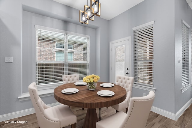 dining area with hardwood / wood-style floors and an inviting chandelier