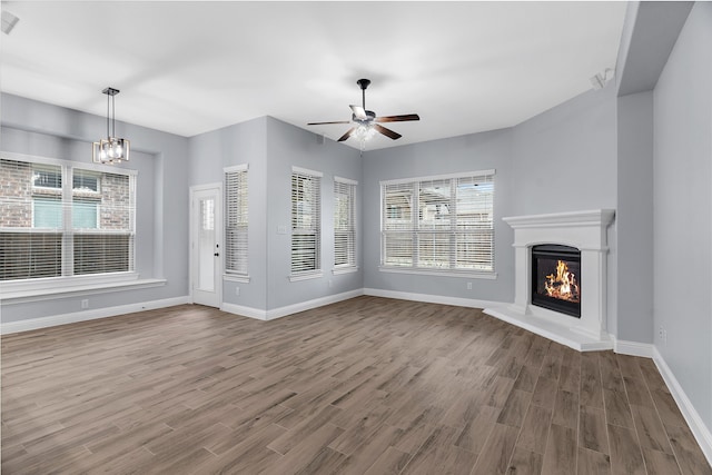 unfurnished living room with hardwood / wood-style flooring and ceiling fan with notable chandelier