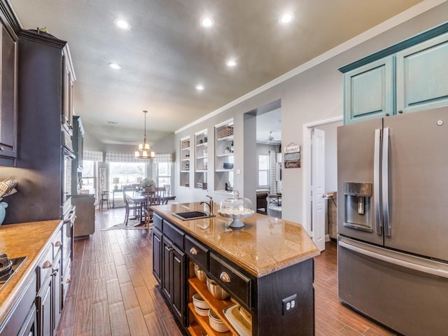 kitchen featuring pendant lighting, a center island with sink, sink, built in features, and appliances with stainless steel finishes