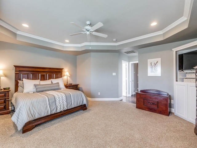 carpeted bedroom with ceiling fan, crown molding, and a tray ceiling