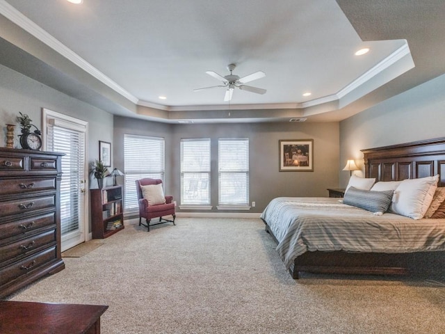 carpeted bedroom with a tray ceiling, ceiling fan, and crown molding