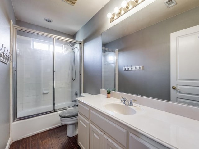 full bathroom featuring hardwood / wood-style floors, vanity, toilet, and enclosed tub / shower combo