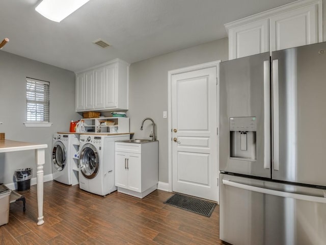 washroom with cabinets, washer and clothes dryer, and sink