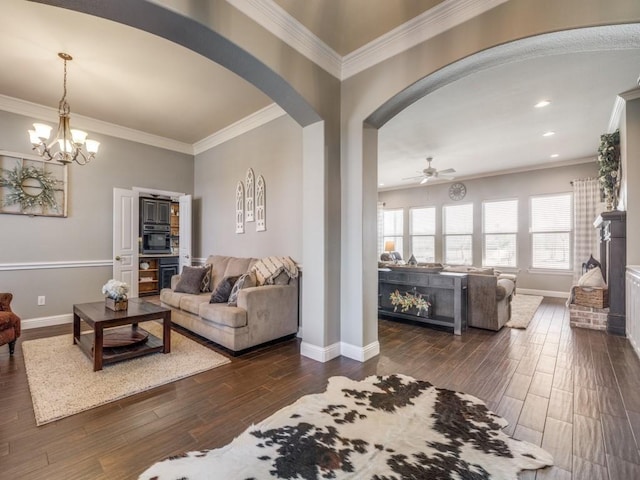 living room featuring ceiling fan with notable chandelier, dark hardwood / wood-style floors, and crown molding