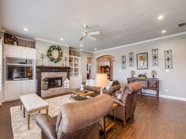 living room featuring dark hardwood / wood-style floors, built in features, ornamental molding, and a fireplace