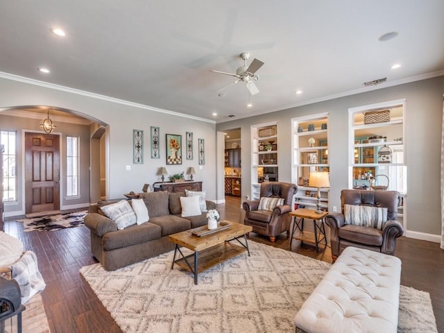 living room featuring built in shelves, ceiling fan, crown molding, and hardwood / wood-style floors