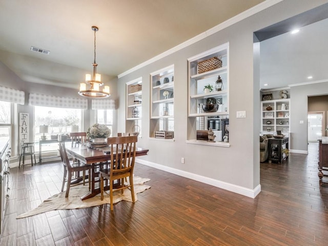 dining area with built in features, ornamental molding, dark hardwood / wood-style floors, and an inviting chandelier