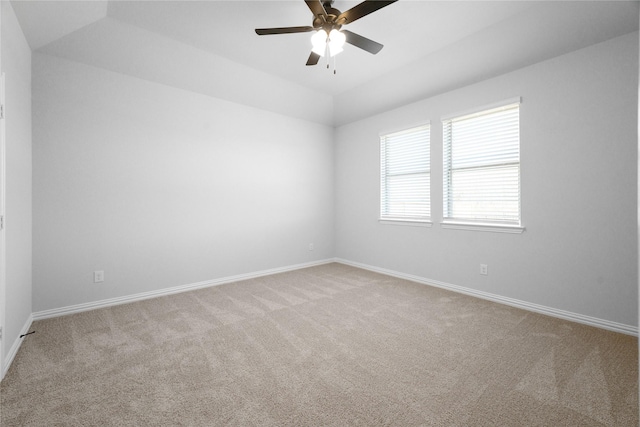 spare room featuring ceiling fan, light colored carpet, lofted ceiling, and a raised ceiling