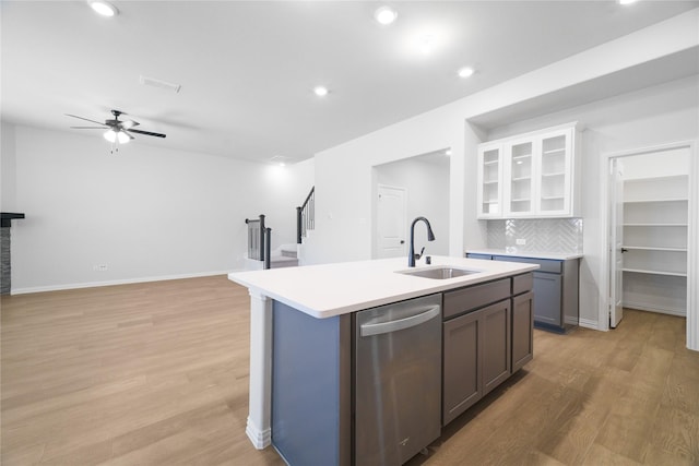 kitchen with sink, tasteful backsplash, light wood-type flooring, stainless steel dishwasher, and white cabinets