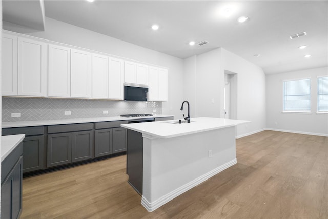 kitchen featuring white cabinetry, sink, gray cabinetry, a kitchen island with sink, and light hardwood / wood-style floors